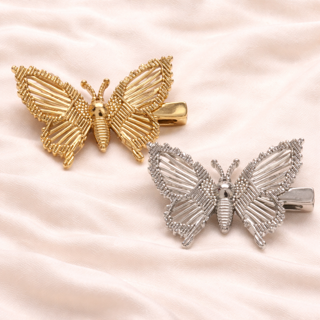 Gold and silver butterfly-shaped hair clips on a soft pink background