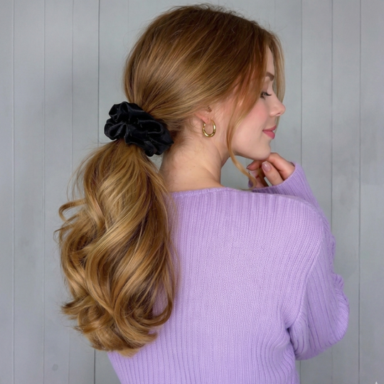 Woman with styled hair and scrunchie against a plain background