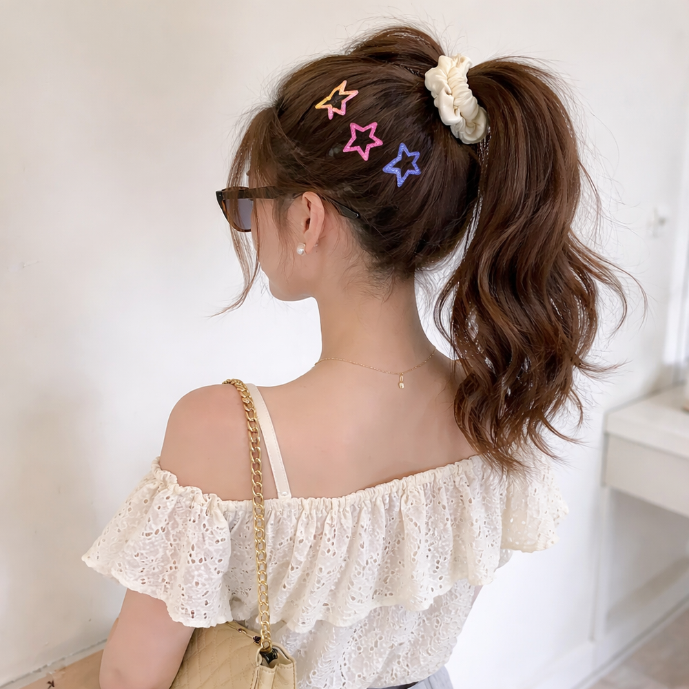 Woman with styled hair featuring colorful hair clips and a ponytail, wearing a white top.