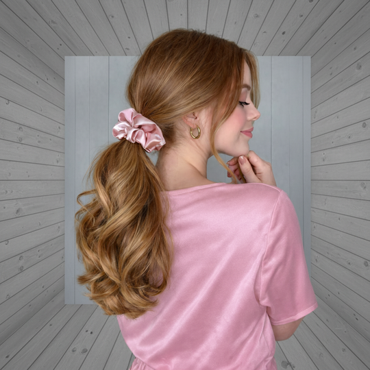 Woman with styled hair wearing a pink top against a gray background