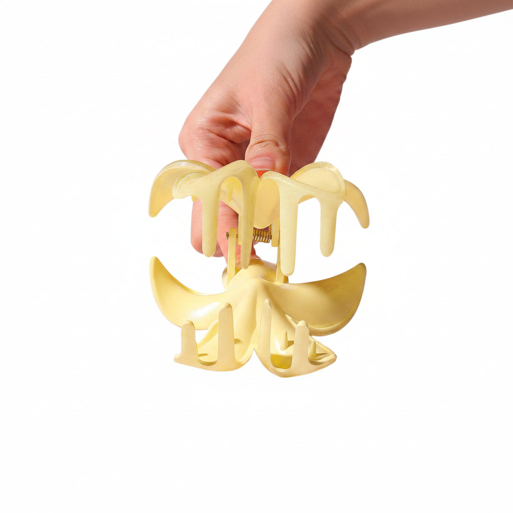 Hand holding a yellow hair clip against a white background