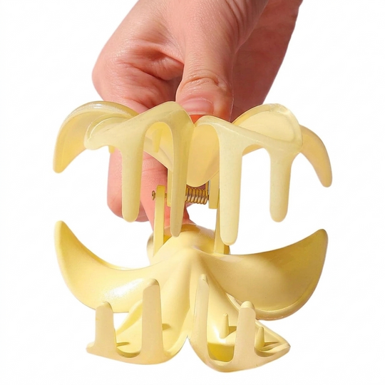 Yellow hair claw clip held by a hand on a white background